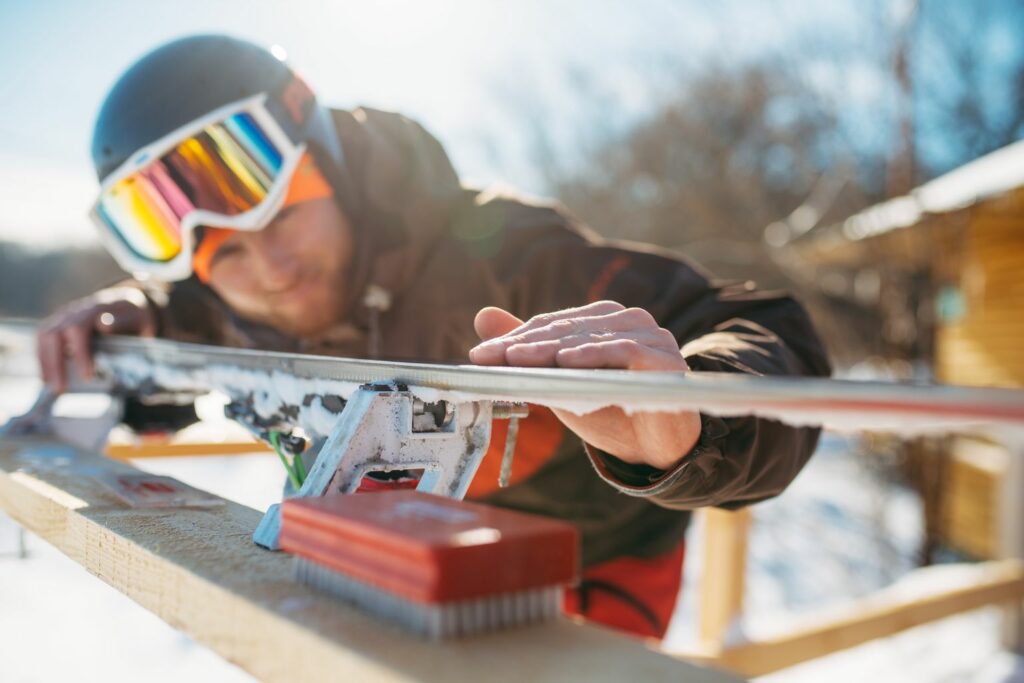 Male skier checks skis before skiing, closeup. Winter active sport, extreme lifestyle. Downhill skiing